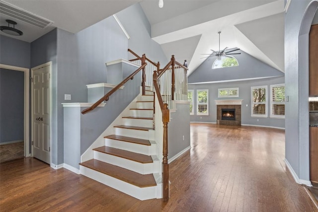 908 Golden Palomino Ct, Austin, TX 78732 - stairway with ceiling fan, wood-type flooring, a tile fireplace, vaulted ceiling, and arched walkways