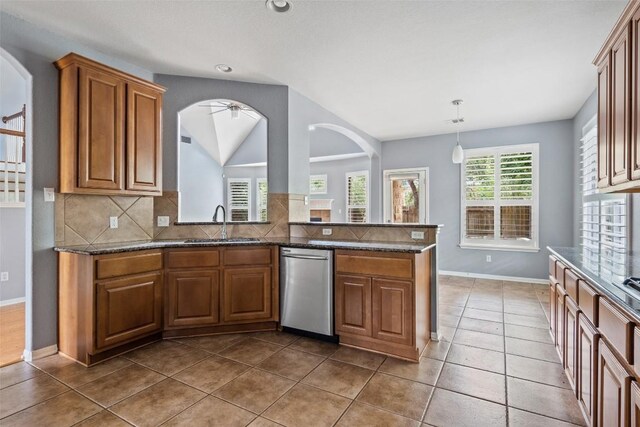 908 Golden Palomino Ct, Austin, TX 78732 - kitchen featuring dishwasher, brown cabinets, tasteful backsplash, dark stone counters, and vaulted ceiling