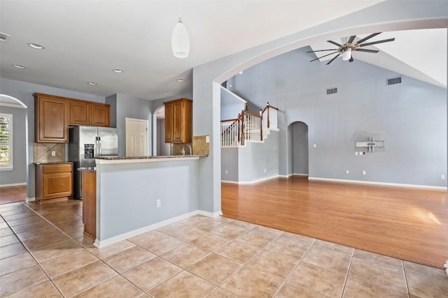 908 Golden Palomino Ct, Austin, TX 78732 - kitchen featuring a ceiling fan, light tile patterned floors, brown cabinets, arched walkways, and stainless steel refrigerator with ice dispenser