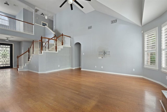 908 Golden Palomino Ct, Austin, TX 78732 - unfurnished living room with ceiling fan, high vaulted ceiling, arched walkways, stairs, and wood finished floors