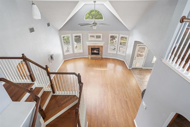 908 Golden Palomino Ct, Austin, TX 78732 - staircase featuring plenty of natural light, a ceiling fan, a fireplace, high vaulted ceiling, and arched walkways