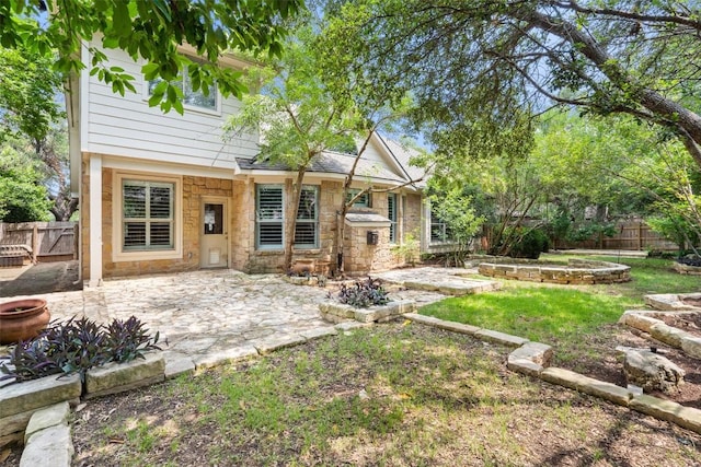 908 Golden Palomino Ct, Austin, TX 78732 - rear view of property featuring stone siding, a patio, and a fenced backyard