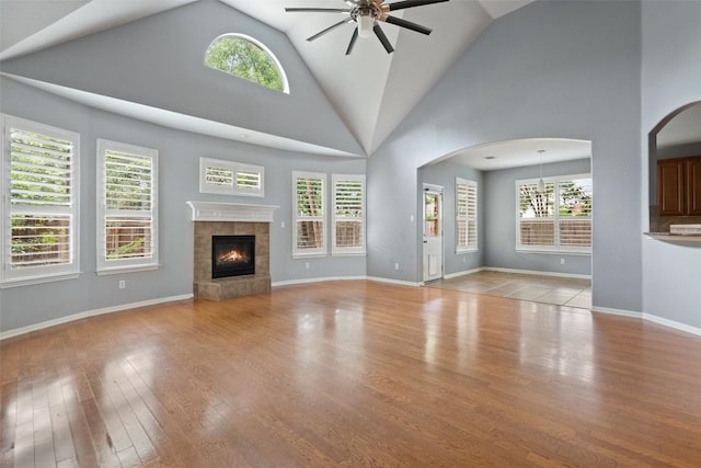 908 Golden Palomino Ct, Austin, TX 78732 - unfurnished living room with ceiling fan, arched walkways, high vaulted ceiling, a tile fireplace, and plenty of natural light
