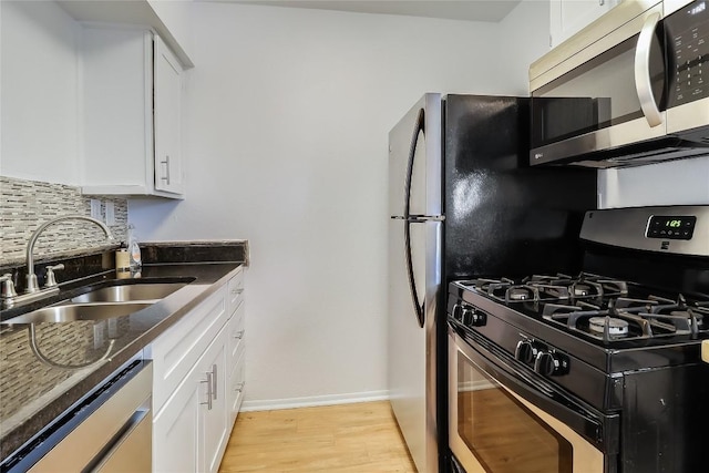 2401 Manor Rd Unit 210, Austin, TX 78722 - kitchen with appliances with stainless steel finishes, dark stone countertops, light wood-style floors, white cabinetry, and tasteful backsplash