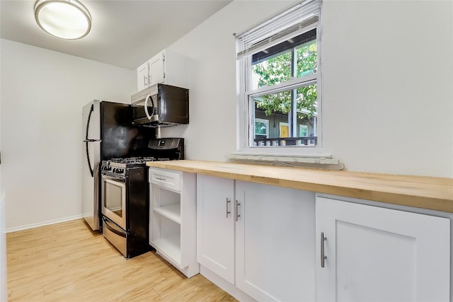 2401 Manor Rd Unit 210, Austin, TX 78722 - kitchen featuring appliances with stainless steel finishes, butcher block countertops, light wood-style floors, white cabinets, and open shelves