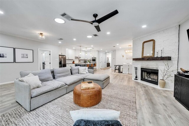 203 Sailors Run, Lakeway, TX 78734 - living room featuring a ceiling fan, ornamental molding, light wood finished floors, a stone fireplace, and recessed lighting