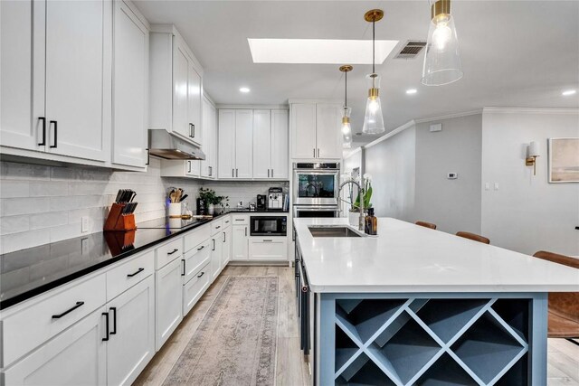 203 Sailors Run, Lakeway, TX 78734 - kitchen featuring open shelves, black microwave, under cabinet range hood, light wood finished floors, and crown molding