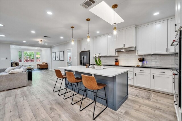 203 Sailors Run, Lakeway, TX 78734 - kitchen featuring refrigerator with ice dispenser, open floor plan, under cabinet range hood, crown molding, and a breakfast bar area