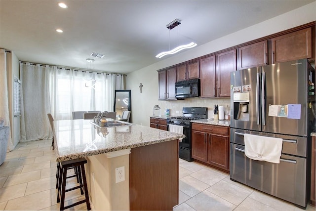 417 Epiphany Ln, Pflugerville, TX 78660 - kitchen with black appliances, light tile patterned flooring, light stone counters, a kitchen breakfast bar, and a center island