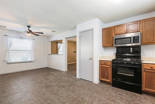 17737 Golden Valley Dr, Manor, TX 78653 - kitchen featuring stainless steel microwave, black range with gas stovetop, a ceiling fan, brown cabinets, and light countertops