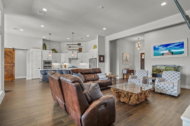205 Honey Locust Cv, Leander, TX 78641 - living room with a barn door, dark wood-style floors, recessed lighting, and a textured ceiling