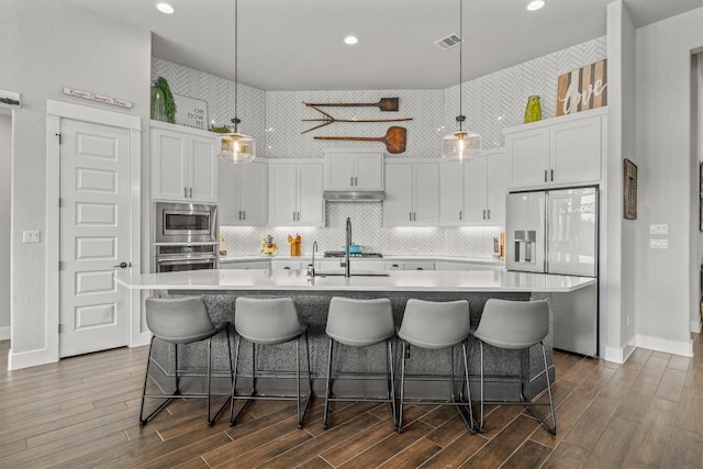 205 Honey Locust Cv, Leander, TX 78641 - kitchen featuring stainless steel appliances, white cabinetry, light countertops, dark wood-style flooring, and recessed lighting