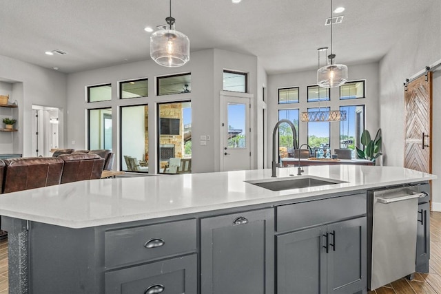 205 Honey Locust Cv, Leander, TX 78641 - kitchen with gray cabinets, a barn door, dark wood-style flooring, a kitchen island with sink, and open floor plan