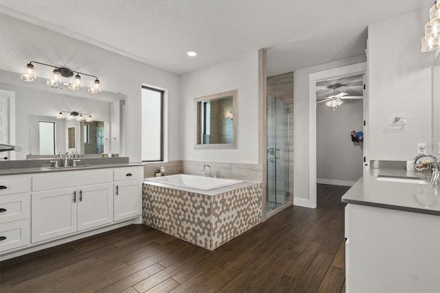 205 Honey Locust Cv, Leander, TX 78641 - bathroom with two vanities, a bath, a ceiling fan, a stall shower, and wood finished floors