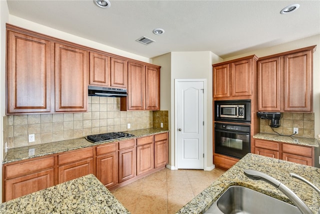 903 Fork Ridge Path, Round Rock, TX 78665 - kitchen featuring stainless steel appliances, light stone countertops, brown cabinetry, tasteful backsplash, and recessed lighting
