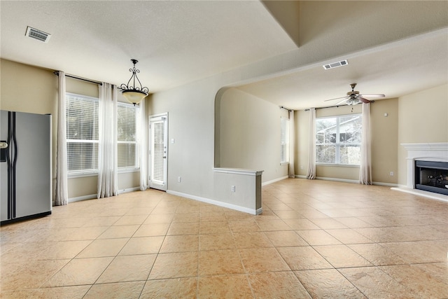 903 Fork Ridge Path, Round Rock, TX 78665 - unfurnished living room with light tile patterned floors, ceiling fan, arched walkways, and a fireplace with raised hearth