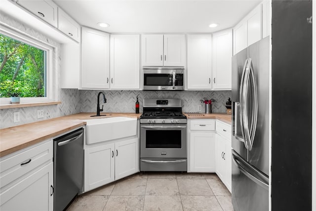 1703 Duke Ave, Austin, TX 78757 - kitchen with stainless steel appliances, butcher block counters, decorative backsplash, white cabinetry, and recessed lighting