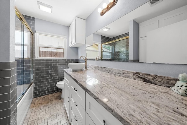 1703 Duke Ave, Austin, TX 78757 - full bath featuring tile walls, vanity, plenty of natural light, enclosed tub / shower combo, and wainscoting
