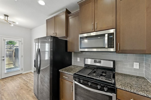 7202 Redding Dr Unit 203, Austin, TX 78745 - kitchen featuring stainless steel appliances, light stone counters, decorative backsplash, and light wood finished floors