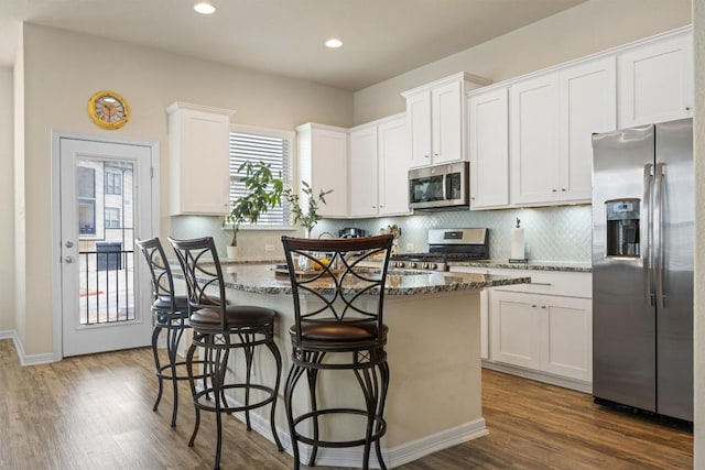 2302 Dillon Pond Ln Unit A, Pflugerville, TX 78660 - kitchen with stainless steel appliances, a kitchen island, dark wood-type flooring, dark stone counters, and decorative backsplash