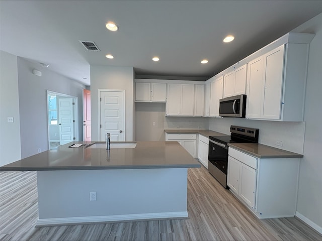 123 Elm Branch Trl, Taylor, TX 76574 - kitchen with stainless steel appliances, light wood-style floors, an island with sink, white cabinetry, and recessed lighting