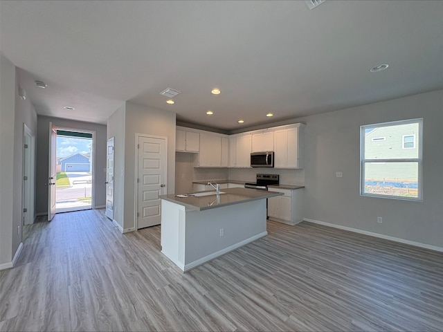 123 Elm Branch Trl, Taylor, TX 76574 - kitchen with appliances with stainless steel finishes, light wood finished floors, white cabinetry, a kitchen island with sink, and recessed lighting