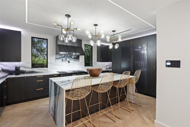 4808 Ranch Rd Unit 2222, Austin, TX 78731 - kitchen featuring stainless steel built in refrigerator, wall chimney range hood, a center island, light stone counters, and a breakfast bar area