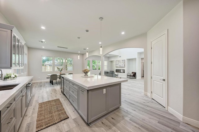 13201 Mansfield Dr, Austin, TX 78732 - kitchen with gray cabinetry, arched walkways, a kitchen island, light wood-type flooring, and recessed lighting