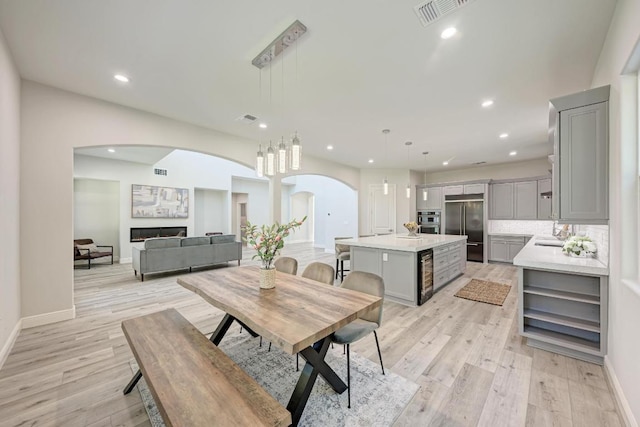 13201 Mansfield Dr, Austin, TX 78732 - dining space with arched walkways, wine cooler, light wood finished floors, and recessed lighting