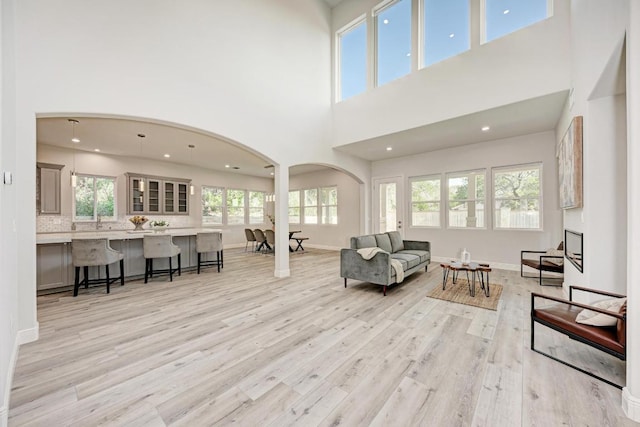 13201 Mansfield Dr, Austin, TX 78732 - living area with arched walkways, light wood-style floors, a high ceiling, and recessed lighting