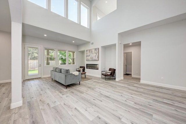 13201 Mansfield Dr, Austin, TX 78732 - living room featuring light wood finished floors, a towering ceiling, and a glass covered fireplace