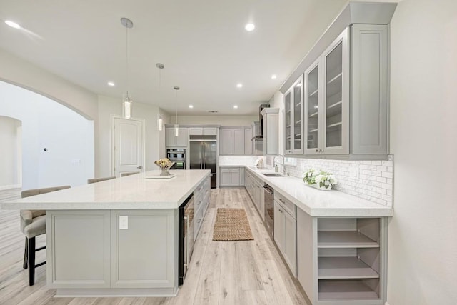13201 Mansfield Dr, Austin, TX 78732 - kitchen featuring appliances with stainless steel finishes, arched walkways, gray cabinets, light wood-style floors, and recessed lighting
