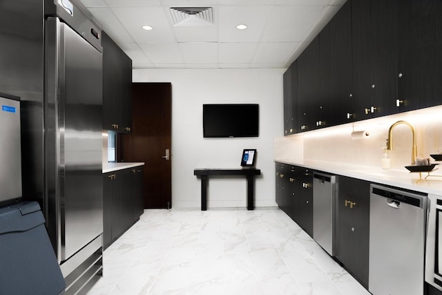 200 Congress Ave Unit 33Bb, Austin, TX 78701 - kitchen featuring stainless steel appliances, dark cabinetry, light countertops, a drop ceiling, and light marble finish flooring