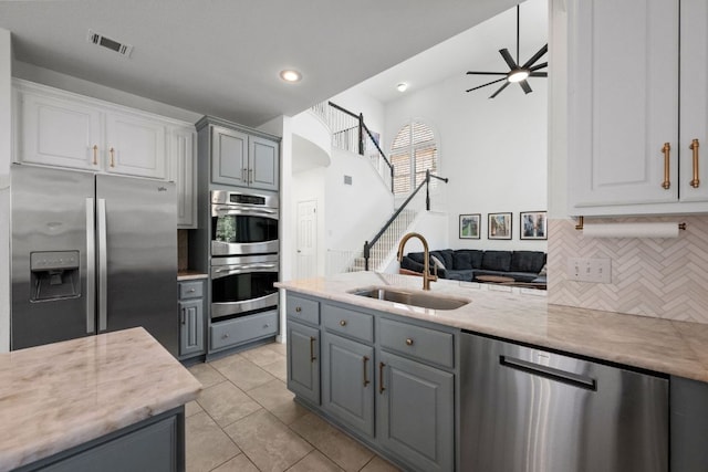 2308 Windswept Dr, Austin, TX 78738 - kitchen featuring appliances with stainless steel finishes, gray cabinets, backsplash, ceiling fan, and white cabinets