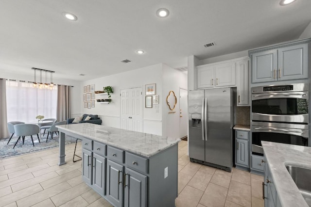 2308 Windswept Dr, Austin, TX 78738 - kitchen with appliances with stainless steel finishes, gray cabinetry, recessed lighting, a center island, and light stone countertops