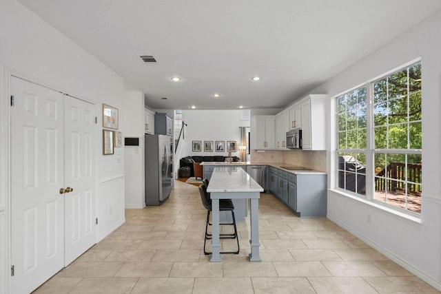 2308 Windswept Dr, Austin, TX 78738 - kitchen featuring stainless steel appliances, a kitchen bar, plenty of natural light, recessed lighting, and backsplash