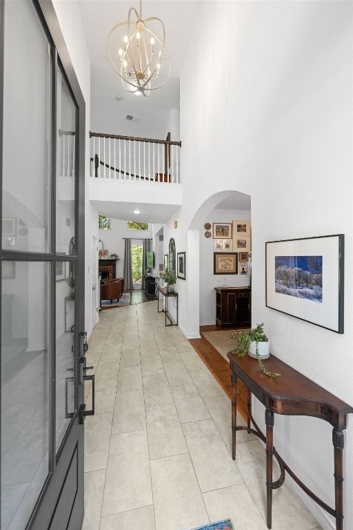 2308 Windswept Dr, Austin, TX 78738 - hallway with arched walkways, a chandelier, a high ceiling, and light tile patterned flooring