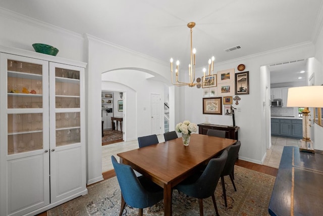 2308 Windswept Dr, Austin, TX 78738 - dining area with arched walkways, ornamental molding, a chandelier, and light wood-type flooring