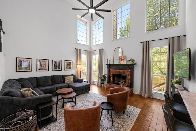 2308 Windswept Dr, Austin, TX 78738 - living area with a ceiling fan, a brick fireplace, a towering ceiling, and hardwood / wood-style flooring