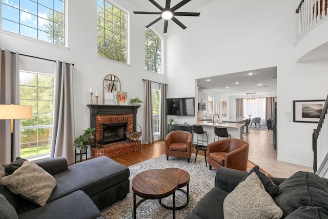 2308 Windswept Dr, Austin, TX 78738 - living area with a ceiling fan, a fireplace, a towering ceiling, healthy amount of natural light, and light wood finished floors