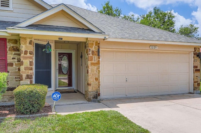 1229 Twin Cv, Kyle, TX 78640 - view of exterior entry with stone siding, roof with shingles, a garage, and driveway