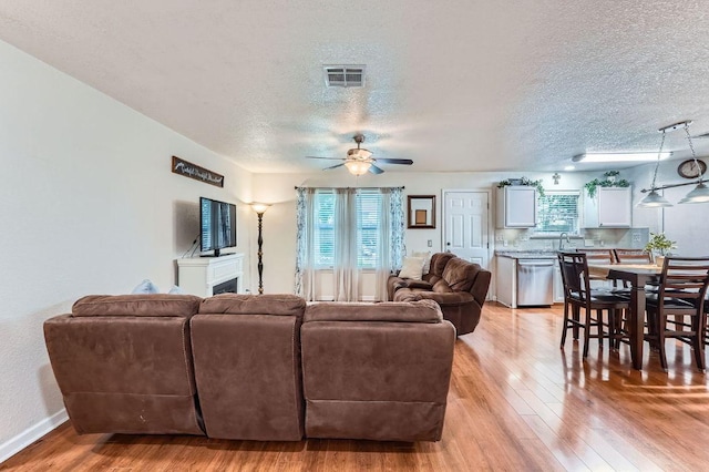 1229 Twin Cv, Kyle, TX 78640 - living area with plenty of natural light, a textured ceiling, light wood-style floors, a fireplace, and ceiling fan