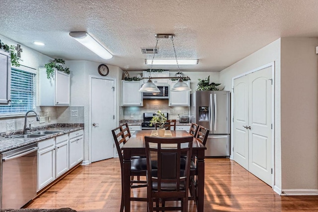 1229 Twin Cv, Kyle, TX 78640 - dining area featuring light wood-style flooring and a textured ceiling