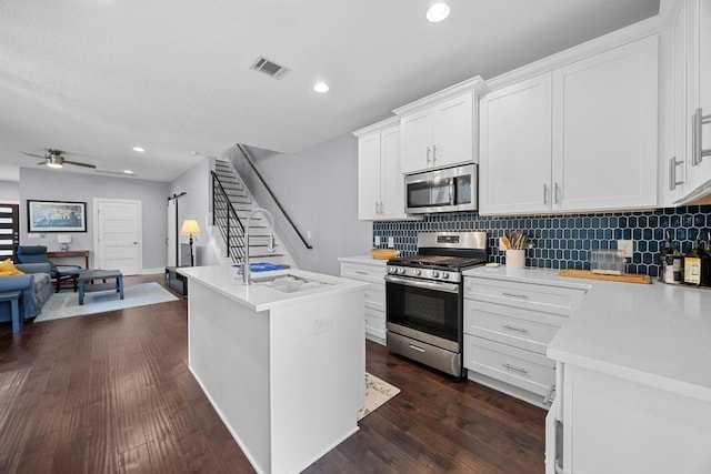 312 Delmar Ave Unit B, Austin, TX 78752 - kitchen with stainless steel appliances, backsplash, light countertops, open floor plan, and white cabinets