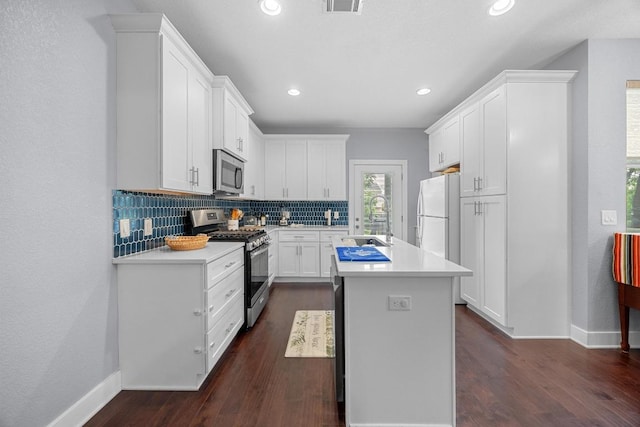 312 Delmar Ave Unit B, Austin, TX 78752 - kitchen featuring appliances with stainless steel finishes, light countertops, tasteful backsplash, a kitchen island with sink, and white cabinetry