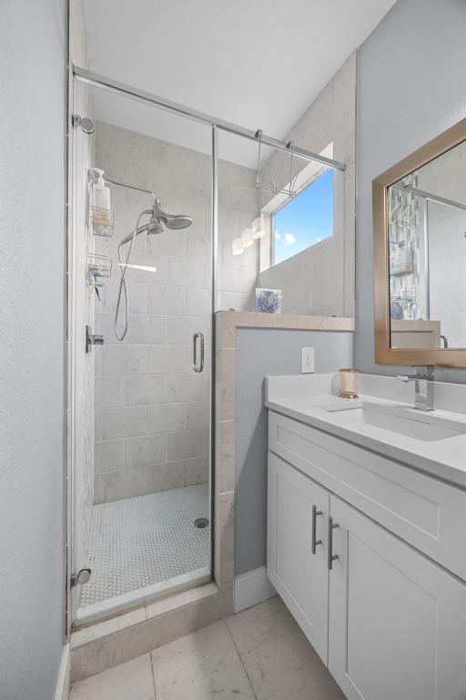 312 Delmar Ave Unit B, Austin, TX 78752 - bathroom featuring vanity, a stall shower, and marble look tiles