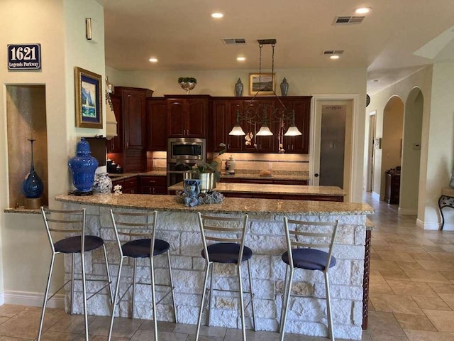 1621 Legends Pkwy, Kingsland, TX 78639 - kitchen with stainless steel microwave, a peninsula, a breakfast bar area, oven, and recessed lighting