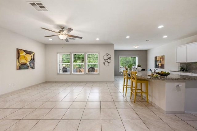 1116 La Conterra Blvd, Georgetown, TX 78626 - kitchen featuring dark stone counters, recessed lighting, a ceiling fan, a breakfast bar area, and white cabinets