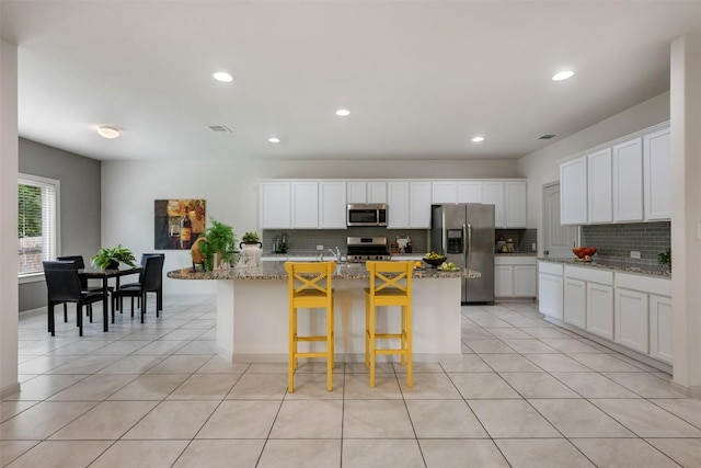 1116 La Conterra Blvd, Georgetown, TX 78626 - kitchen with stainless steel appliances, decorative backsplash, a kitchen island with sink, light tile patterned floors, and recessed lighting