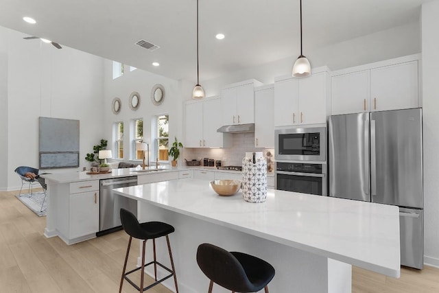 2705 Sage Ranch Dr Unit 19, Leander, TX 78641 - kitchen with stainless steel appliances, under cabinet range hood, a peninsula, backsplash, and white cabinets